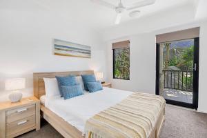 棕榈湾极乐园公寓的一间卧室配有一张带蓝色枕头的大床