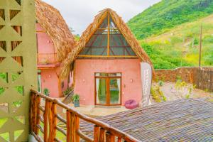 圣维罗尼卡Casa Mambo Salinas的一座带茅草屋顶的粉红色小房子