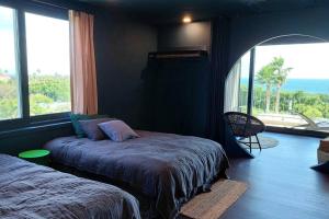 西归浦市Vila Omuamua的一间卧室设有两张床和大窗户