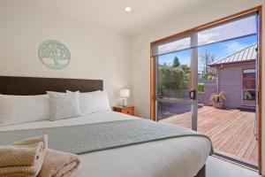 汉默温泉Welcome Home - Hanmer Springs Holiday Home的一间卧室设有一张床和一个滑动玻璃门