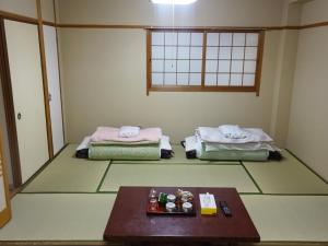 大阪Imazato Ryokan - Vacation STAY 02547v的一间设有两张床和一张桌子的房间