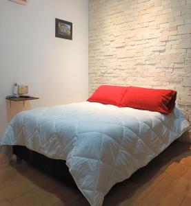 韦拉克鲁斯Habitaciones amuebladas Veracruz Logos的一张带红色枕头和砖墙的床