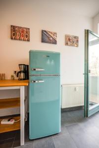 莱比锡Arbio I Modern Apart near Leipzig Stötteritz的桌子旁的厨房里的一个蓝色冰箱