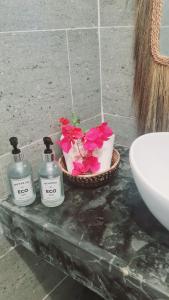 江比阿Garden Beach Bungalows Jambiani的浴室的柜台上放了三瓶肥皂和鲜花