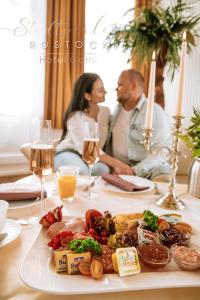 罗斯托克洛斯托克斯达特皮尔酒店的坐在餐桌上吃一盘食物的男人和女人