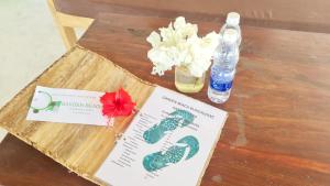 江比阿Garden Beach Bungalows Jambiani的一张桌子,上面放着一本书,鲜花和一瓶水