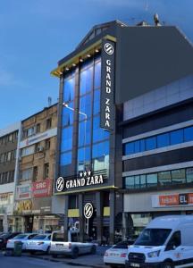 开塞利Grand Zara Hotel的一座大型建筑,前面有汽车停放