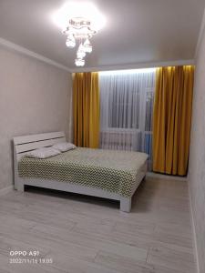 科克舍套Мухтара Ауэзова 205的一间卧室配有床和黄色窗帘