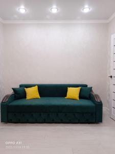 科克舍套Мухтара Ауэзова 205的客房内的绿色沙发,配有两个黄色枕头