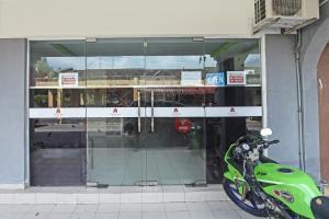 瓜埠OYO 90324 Muar Station Hotel的停在商店前的绿色摩托车