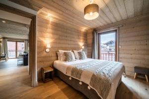 谷雪维尔Apartment Cervino Monriond Courchevel - by EMERALD STAY的一间卧室设有一张床和一个大窗户