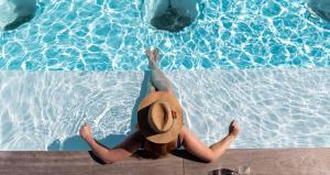 开普敦ANEW Hotel Green Point Cape Town的坐在游泳池的戴帽子的女人