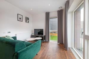 伦敦Stayo Apartments Barking Wharf的客厅设有绿色沙发和大窗户