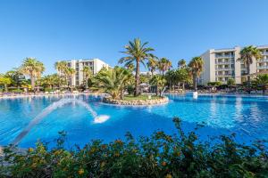 伊斯兰蒂拉Estival Islantilla的一座棕榈树和建筑的大型游泳池