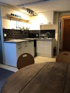 夏蒙尼-勃朗峰B&B Chalet Les Frenes的厨房配有白色橱柜和木桌
