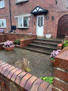 Spacious 3 bedrooms house in Bolton Upon Dearne Up to 6 Guests!的砖屋,有楼梯通往白色的门