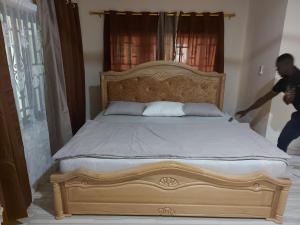 库马西Masbella Airbnb的一个人在卧室里打扫床
