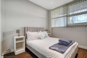 伦敦Cosy 1-Bed by Heathrow Airport的白色卧室设有一张带窗户的床