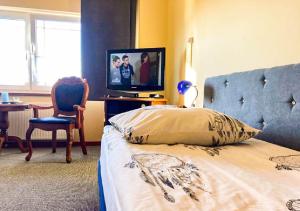 谢维日Noclegi Prestige的一间卧室配有一张床、电视和椅子