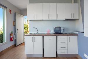 加尔达尔Estudio Lua的厨房配有白色橱柜和微波炉