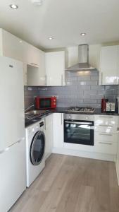 利物浦Large 6 bedroom duplex - perfect for large family的厨房配有白色橱柜、洗衣机和烘干机