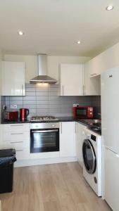利物浦Large 6 bedroom duplex - perfect for large family的厨房配有白色橱柜、洗衣机和烘干机