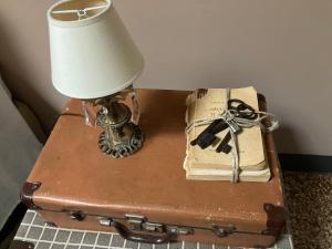 博洛尼亚BLQ 01精品住宿加早餐旅馆的桌子上的一盏灯,上面有行李箱和一本书