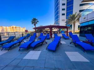 迪拜Exquisite, luxe 1BD Apartment, Unparalleled Sea Views, Prime Dubai Marina Location & Full Kitchen by "La Buena Vida Holiday Homes的庭院里设有凉亭,摆放着蓝色的椅子