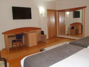 费罗尔Real Ferrol的酒店客房设有两张床、一张桌子和一台电视。