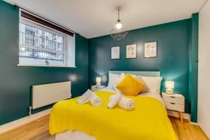 斯蒂夫尼奇Spacious Luxury Service Apartment Stevenage Town Centre family or business的一间卧室配有黄色的床和2条毛巾