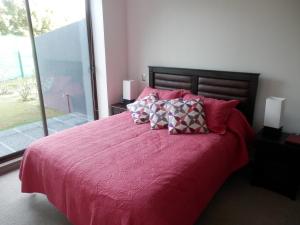 普孔Casa Costa Pucón的卧室配有一张大床,提供红色床单和枕头