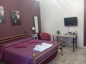 罗马B&B "Feelgood"的一间卧室配有一张紫色床、一张桌子和一台电视机。