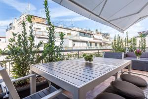 雅典Emilie in Athens - Central chic flat with terrace Syntagma E1的阳台配有桌椅,与大楼相连