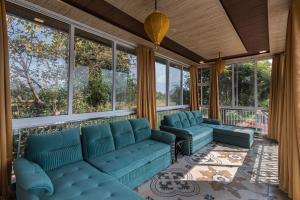 卡尔贾特SaffronStays Olive Greens, Karjat的一个带蓝色沙发和窗户的门廊