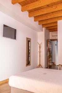 瓜达卢佩ANJ Alojamientos的卧室设有白色的床和木制天花板。