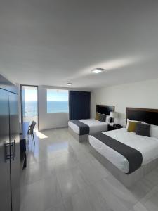 马萨特兰Hacienda Mazatlán sea view的酒店客房带两张床和一张桌子以及椅子。