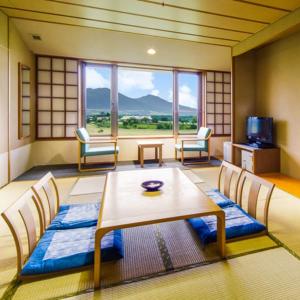 真庭市Kyukamura Hiruzen-Kogen的客房设有桌椅和大窗户。