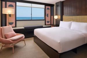檀香山Hotel Renew的卧室配有床、椅子和窗户。