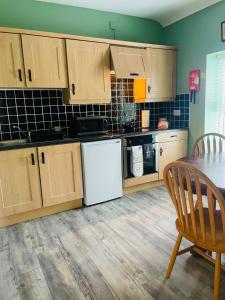 伦敦德里Heights View Apartment的厨房配有木制橱柜、桌子和桌椅