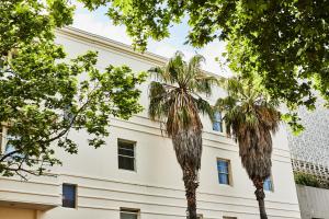 墨尔本王子酒店的一座白色的建筑,前面有棕榈树