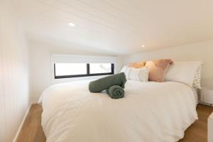 赫斯基森Husky Tiny Home by Experience Jervis Bay的白色卧室配有一张带枕头的大白色床