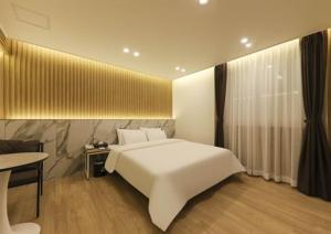 光州Gwangju Brown Dot Chungjang的卧室配有一张白色的大床和一张桌子