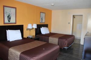 红木城红木城巴吉旅馆的两张床位于带黄色墙壁的酒店客房