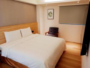 永和浮逸饭店的卧室配有白色的床和椅子