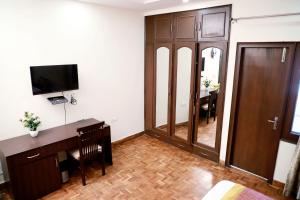 新德里Fortune Home Service Apartment 3Bhk,E-28 Saket 1B的一间带书桌和电视的客厅以及一间房间。