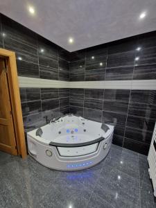 韦尔维耶Tendresse - Espace Détente Ensival的浴室设有按摩浴缸,铺有黑色瓷砖。