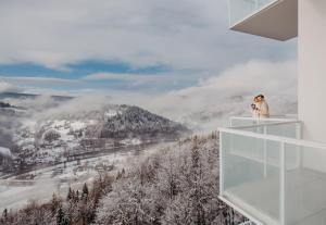 维斯瓦Crystal Mountain Hotel Wisła的站在一个阳台上,画着白雪 ⁇ 的山