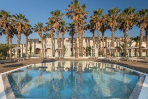 卡尔扎迈纳Porto Bello Beach Hotel的一座楼前种有棕榈树的游泳池