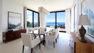 加拉班Navy Hill Resort的一间带桌子和白色椅子的用餐室