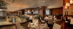 纳威孟买Fortune Select Exotica, Navi Mumbai - Member ITC's Hotel Group的一间设有白色桌椅的餐厅和一间酒吧